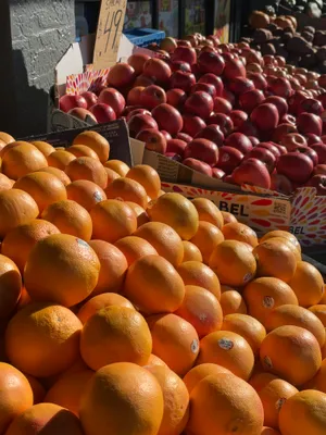 Grapefruits and red apples piled in cardboard boxes at a sunny outdoor fruit stand
